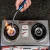 Long neck electric arc lighter being used to ignite a compatible kitchen gas stove